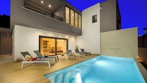 Uma área moderna com piscina ao ar livre, espreguiçadeiras e espaço para refeições.