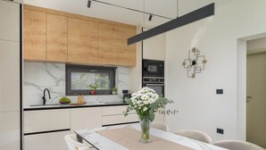 Uma cozinha moderna com armários de madeira, forno embutido e um espaço de jantar com mesa e cadeiras.