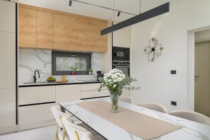 Eine moderne Küche mit Holzschränken, einem eingebauten Ofen und einem Essbereich mit Tisch und Stühlen.
