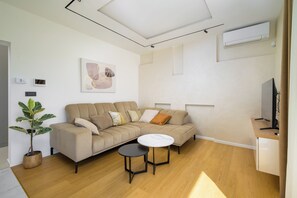 Ein modernes Wohnzimmer mit einer Couch, einem kleinen runden Tisch und einer Zimmerpflanze.