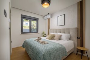 Ein Schlafzimmer mit Bett, Fenster, Wandklimaanlage und einem kleinen Tisch.