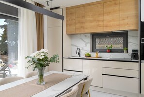 Eine moderne Küche mit Marmorarbeitsplatte, Holzschränken und einem Essbereich mit Tisch und Stühlen.