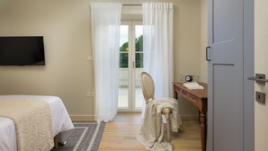 Ein Schlafzimmer mit einem Bett, einem Schreibtisch mit Stuhl, einem Fernseher und einer Schiebetür.