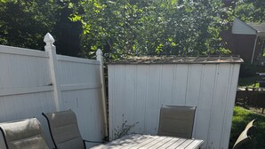 Eine Terrasse im Freien mit Tisch und Stühlen, umgeben von einem weißen Zaun.
