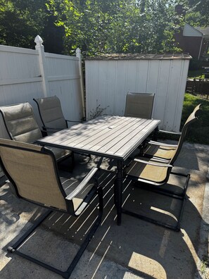 Eine Terrasse im Freien mit Tisch und Stühlen, umgeben von einem weißen Zaun.