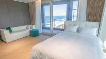 Una habitación de hotel moderna con una cama grande, un sofá y vistas a la playa.