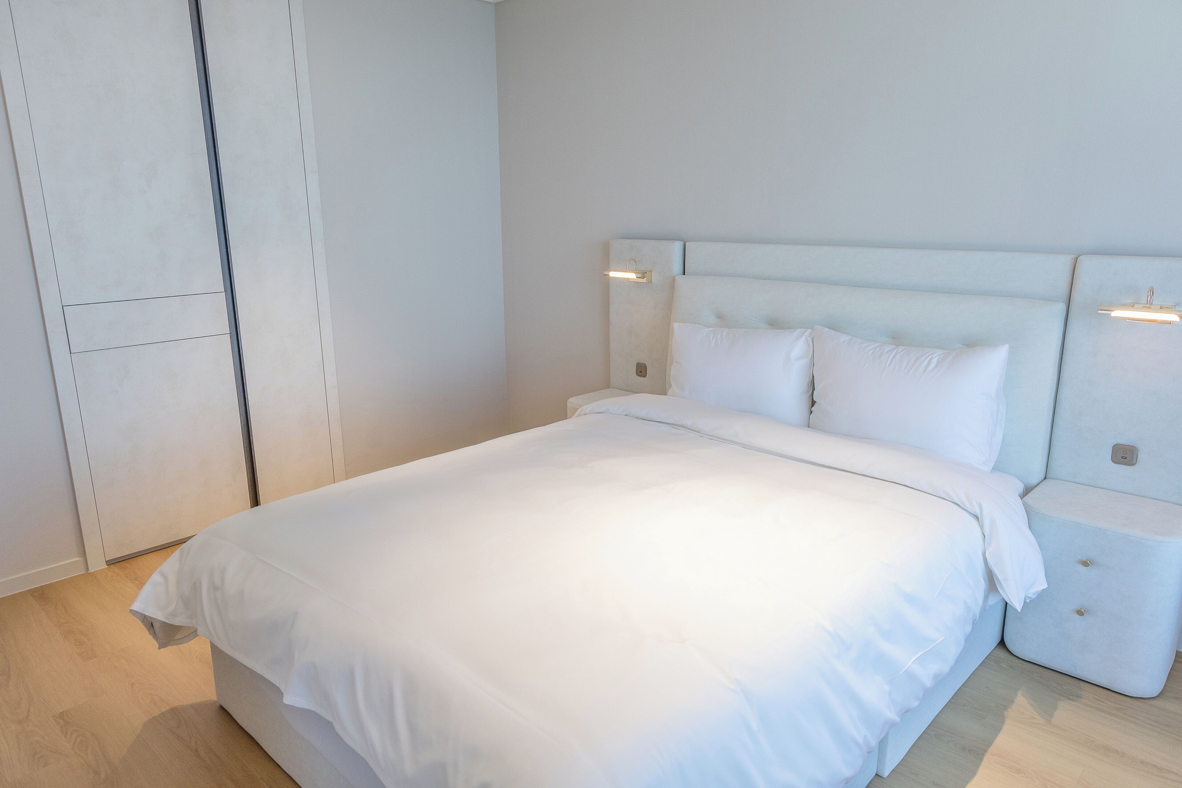 A bedroom with a bed, bedside tables, and a wardrobe.