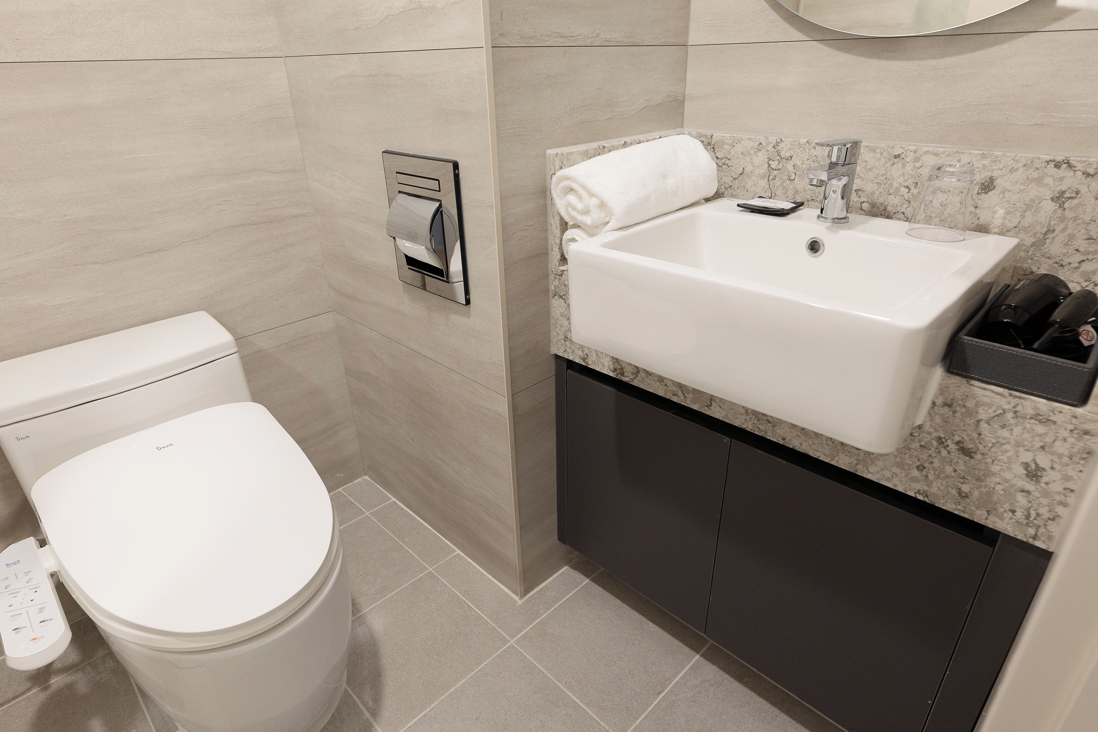 A modern bathroom with a toilet, a sink, and a towel rack.
