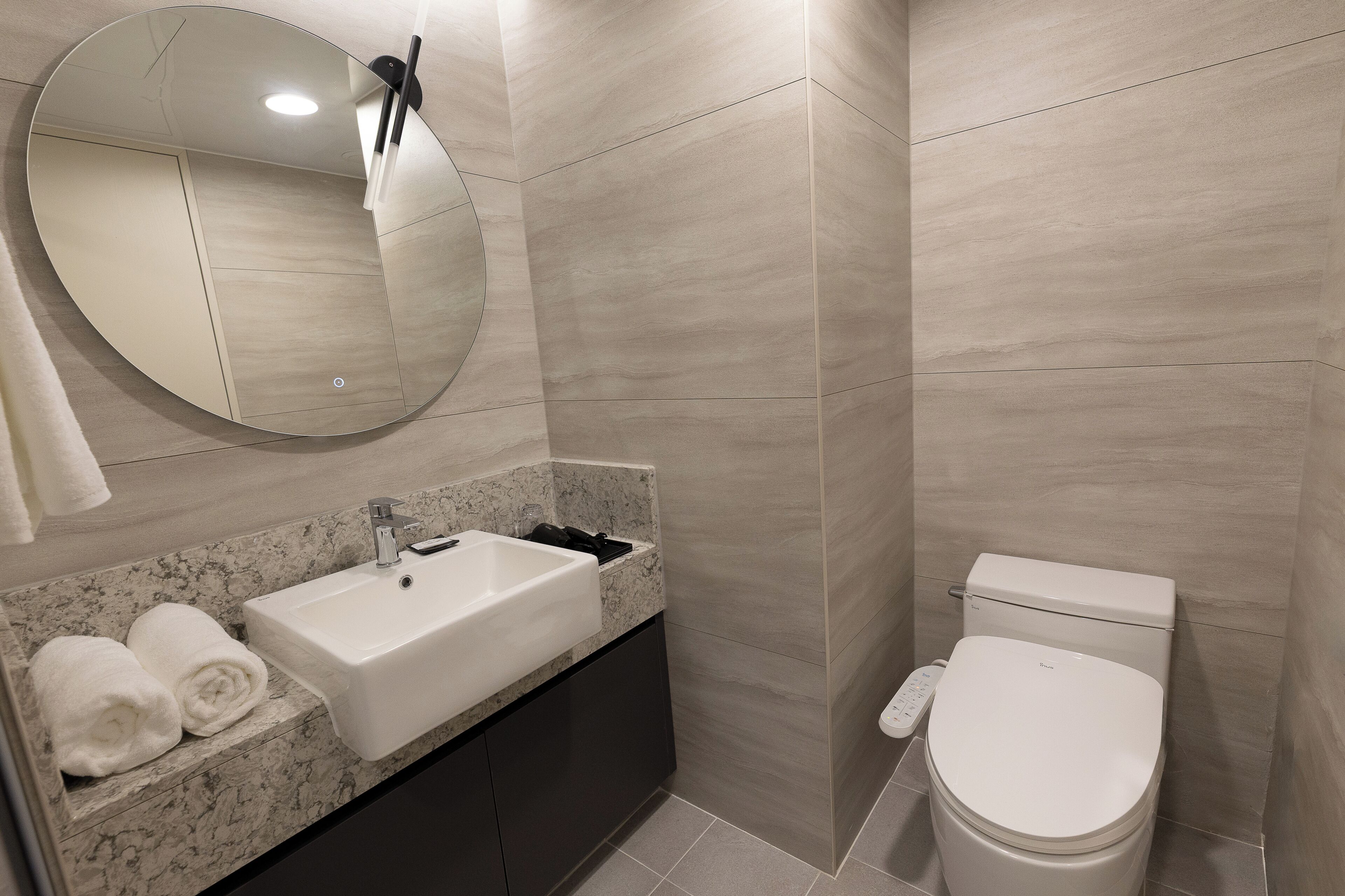 Un bagno moderno con lavandino, specchio e water.