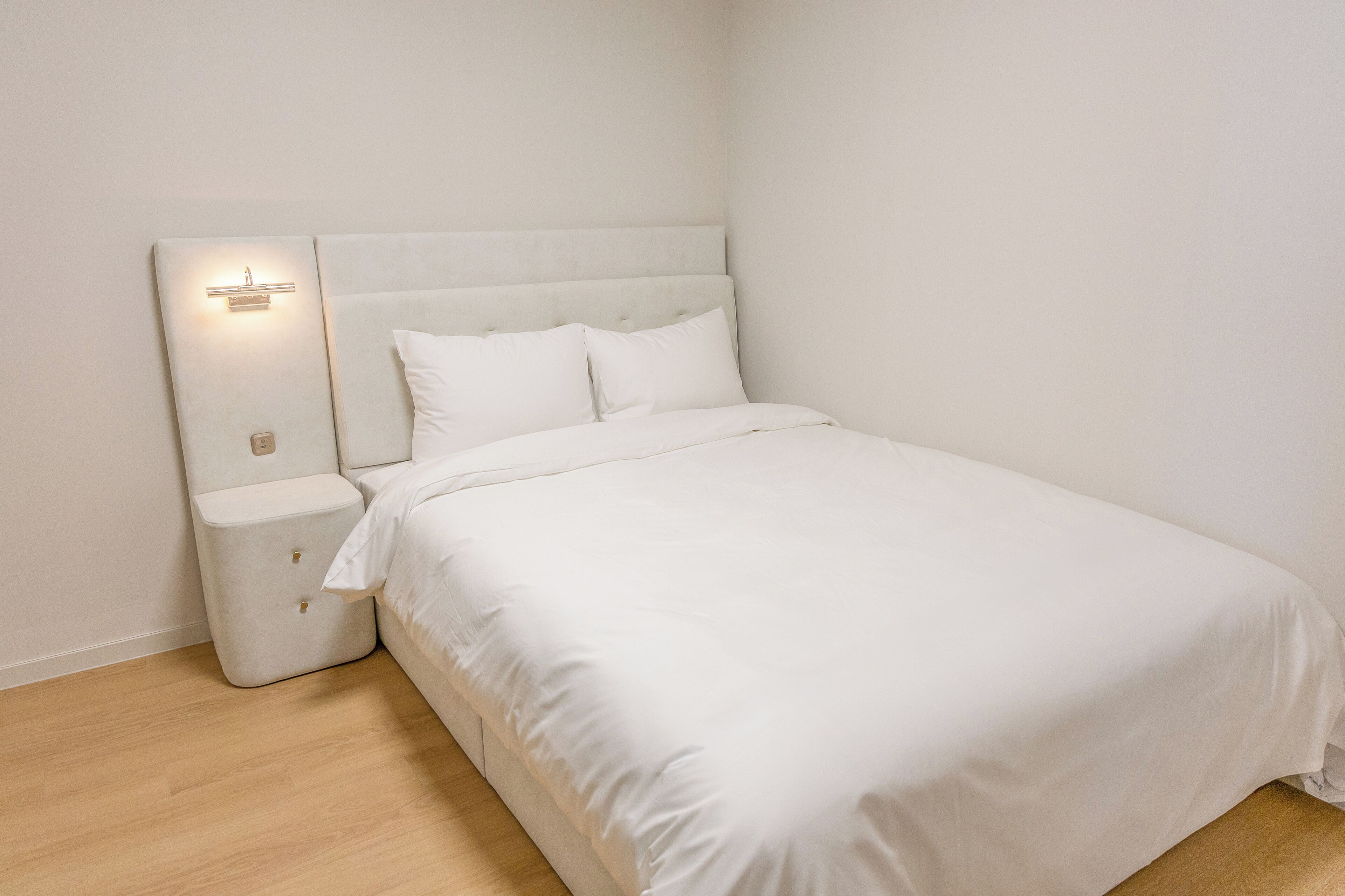 A single-bed room with a headboard, bedside tables, and a light fixture.