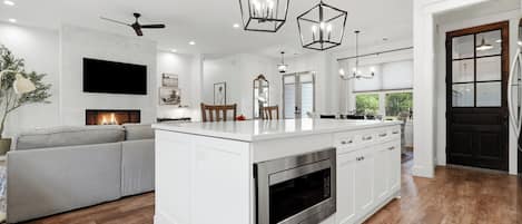 A modern kitchen with a central island, built-in oven, and pendant lighting.