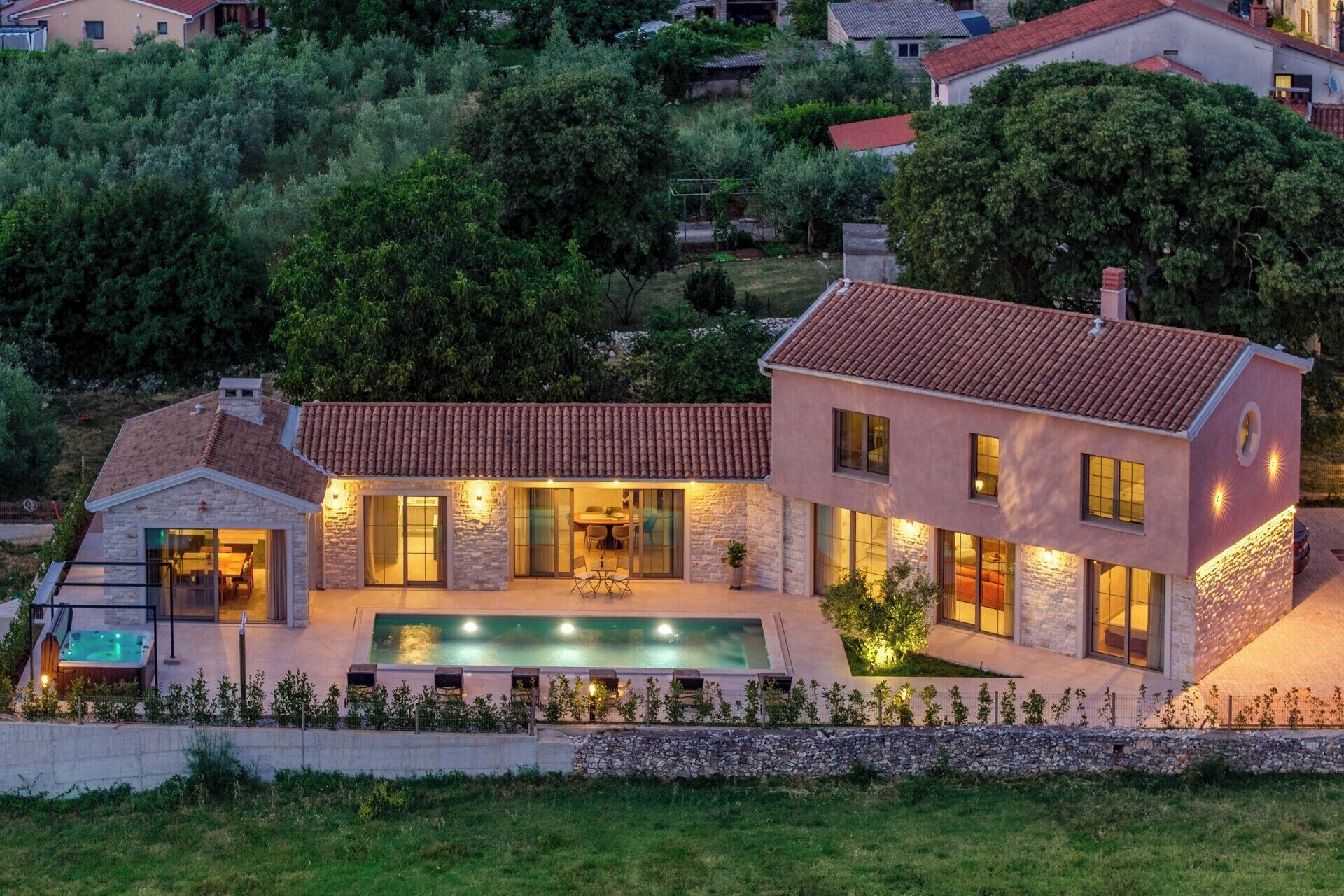 Une maison moderne dotée d’une piscine, de murs en pierre et d’un éclairage extérieur soigné.