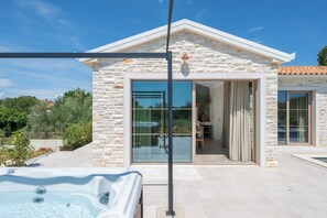 A modern house with a stone facade, large glass doors, and a hot tub in the foreground. - Vila Da Ella by Istrabook (Krnica)