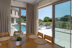 A dining area with a view of a swimming pool and outdoor seating. - Vila Da Ella by Istrabook (Krnica)