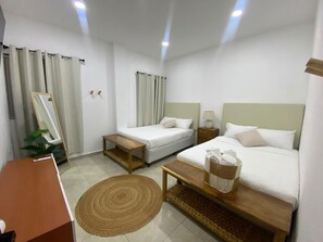 A hotel room with two beds, a desk, a mirror, a plant, and a woven rug. - Beachfront Luxury Villa with Private Pool in the fantastic Costa Del Sol (San Pedro Masahuat)