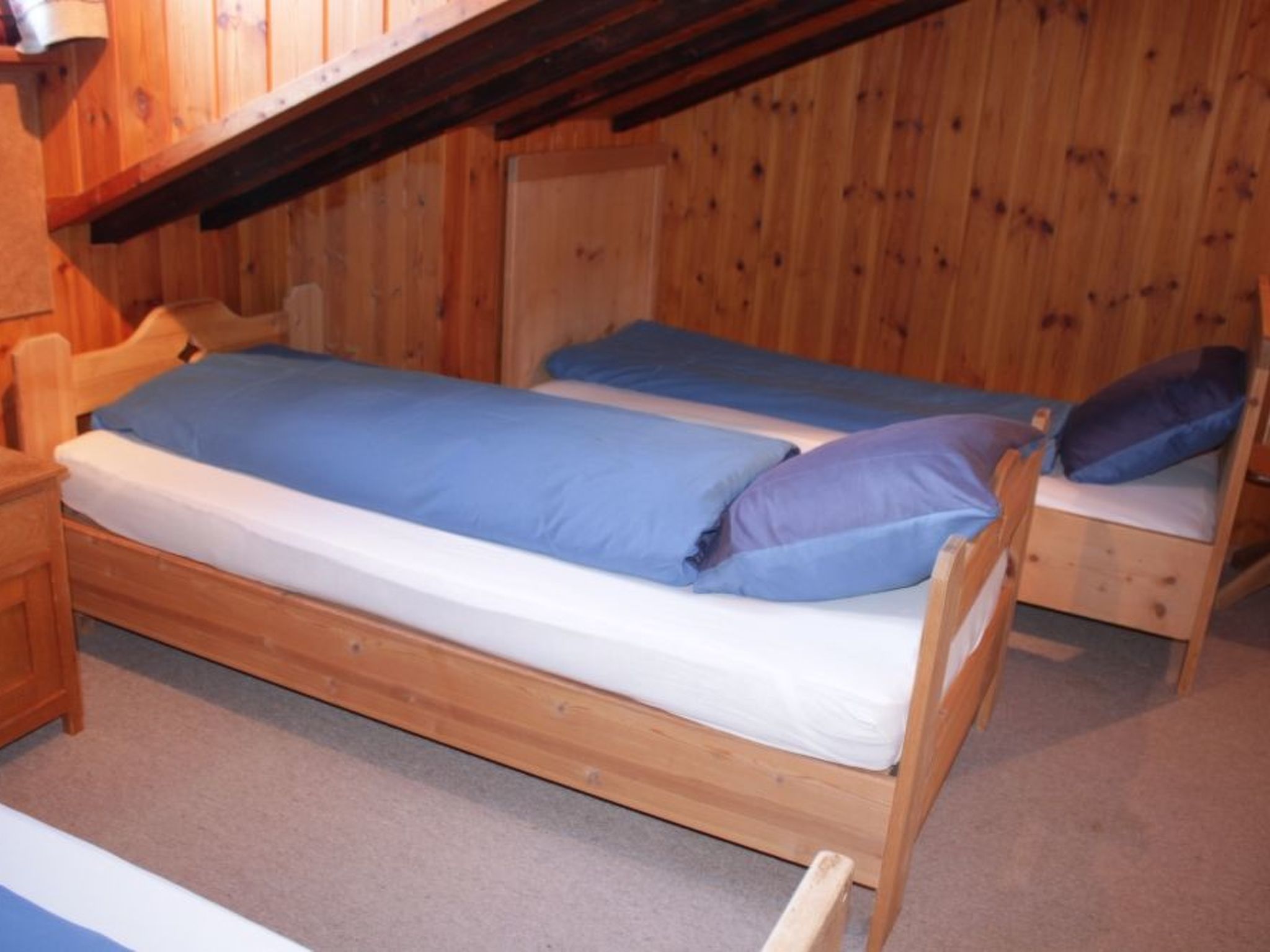 Un lit superposé en bois avec un matelas et des oreillers, une table de chevet en bois et une tête de lit en bois.