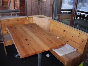 Un banc en bois doté d’un siège et d’un dossier rembourrés, placé devant une fenêtre.