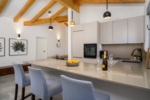 A modern kitchen with a central island, bar stools, a wine bottle, and glasses. - Villa Oliver (Istria - Buje) (Buje)