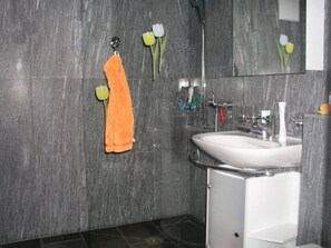 A bathroom with a white sink, a mirror, and a towel rack with an orange towel. - Köppel, (Disentis/Mustér), 1053 by Interhome (Disentis)