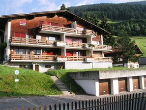 A multi-story building with balconies, a parking area, and a natural landscape in the background. - Köppel, (Disentis/Mustér), 1053 by Interhome (Disentis)
