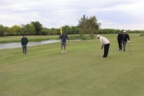 A golf course with a water body and trees in the background. - Huge Backyard • Community Pool • Near Arena (Pharr)