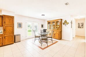 A spacious kitchen with a dining area, featuring a large cabinet, a refrigerator, and a dining table with chairs. - Huge Backyard • Community Pool • Near Arena (Pharr)