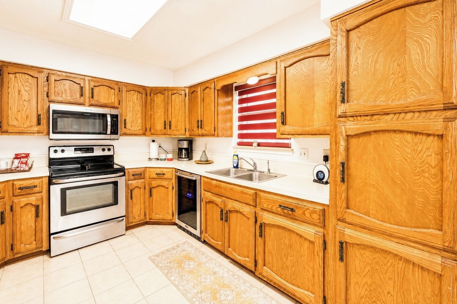 Una cocina con armarios de madera, microondas, horno, lavavajillas y un lavabo.