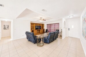 A spacious living room with a ceiling fan, a large entertainment unit, and a seating area with sofas and a coffee table.