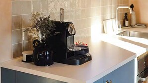 Ett kök med en kaffemaskin, en diskho och ett fönster.