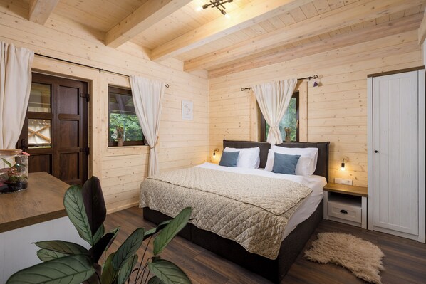 Ein Schlafzimmer einer Holzhütte mit einem Bett, Nachttischen und Vorhängen.