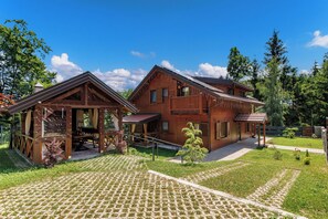 A two-story wooden house with a balcony, a covered porch, and a paved driveway. - Wooden wellness home with sauna in the heart of Gorski Kotar (Fužine)