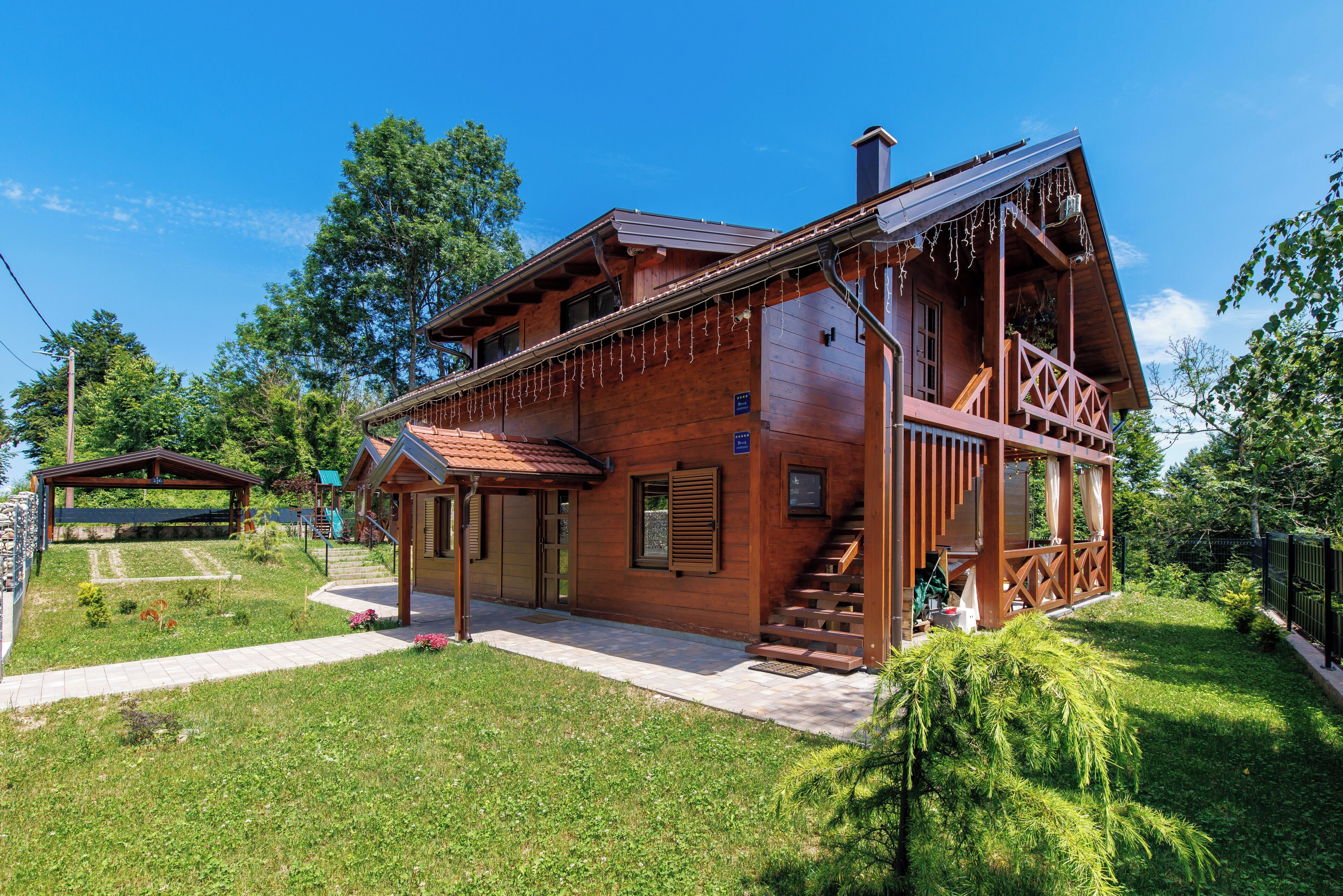 A wooden cabin with a porch, a staircase, and a small garden.