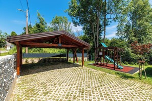 A covered pavilion with a playground, including a slide, in a park setting. - Wooden wellness home with sauna in the heart of Gorski Kotar (Fužine)