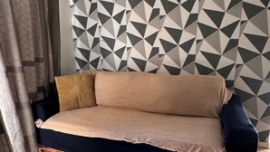 Una sala de estar moderna con una pared de diseño geométrico, un sofá y piso de madera.