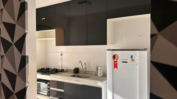 Una cocina moderna con armarios negros, un refrigerador blanco y una estufa a gas.