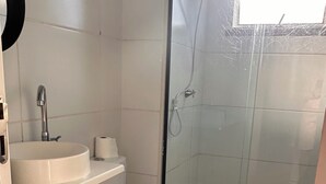 Un baño con inodoro, lavamanos, ducha y una alfombra pequeña.