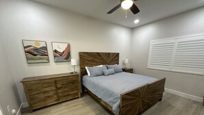 Ein Schlafzimmer mit einem hölzernen Bett, einem Nachttisch, einer Kommode und zwei an der Wand befestigten Bildern.