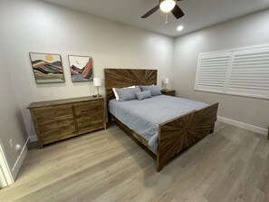 Ein Schlafzimmer mit einem hölzernen Bett, einem Nachttisch, einer Kommode und zwei an der Wand befestigten Bildern.