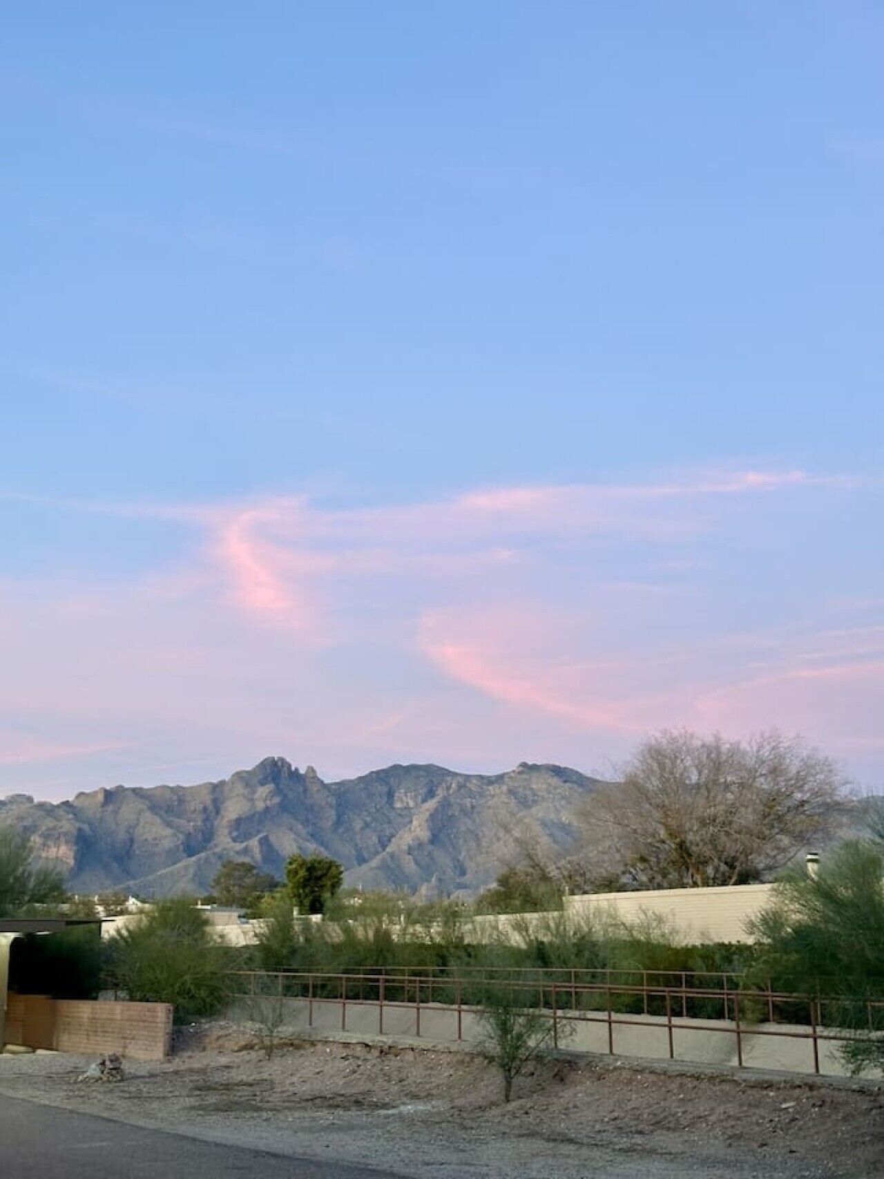 Paisaje montañoso con cielo despejado y una cerca en primer plano.