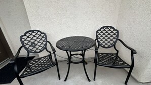 Ein kleiner Sitzbereich im Freien mit einem runden Tisch und zwei Stühlen.