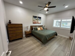 Ein Schlafzimmer mit Bett, einem Holzkapfen, Nachttischen, Deckenventilator und einem Fenster.