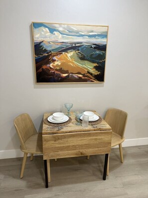 Ein Esstisch mit zwei Stühlen, ein Bild an der Wand und ein Holzboden.