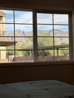 Ein Zimmer mit großem Fenster und Blick auf eine gebirgige Landschaft.