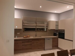 Eine moderne Küche mit Geschirrspüler, Backofen und einem Fenster über der Spüle.