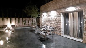 An outdoor patio area with a stone wall, seating, and a sliding glass door. - Exceptional villa with a pool (Essaouira)