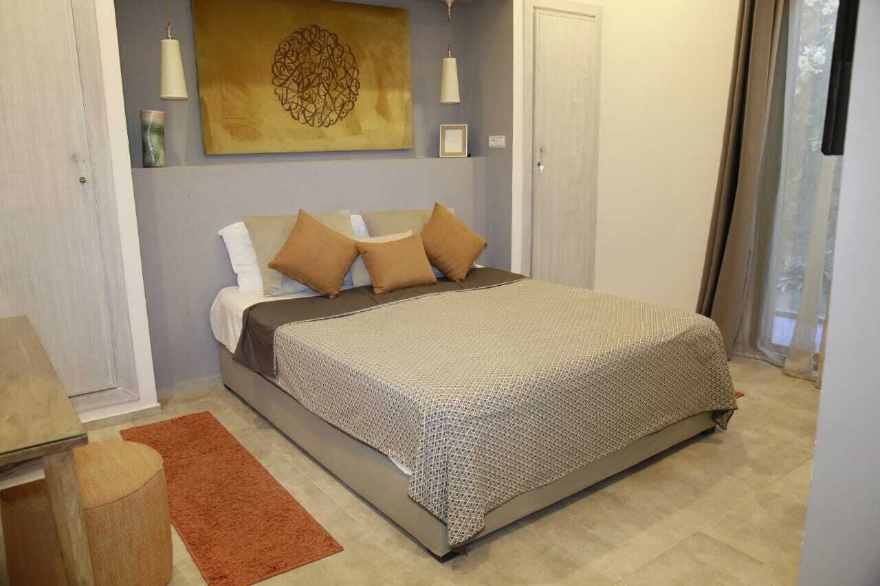 Ein Schlafzimmer mit einem Bett, Kissen, einem Teppich, einem Wandbild und einer Tür.