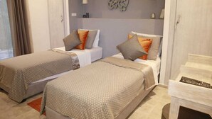A hotel room with two beds, a small table, a decorative wall piece, and a door. - Exceptional villa with a pool (Essaouira)