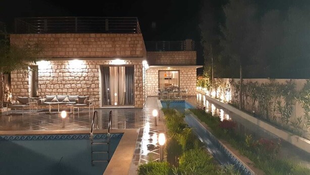 A stone building with a pool, outdoor seating, and a well-lit patio area. - Exceptional villa with a pool (Essaouira)