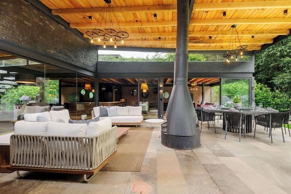 A central wood-burning fireplace anchors the covered terrace's dining and lounge zones