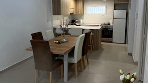 Een moderne keuken met houten kastjes, een eettafel met stoelen, en een bijzettafeltje met een bloemenvaas.